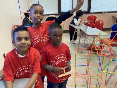 Students showing off their airport built out of straws